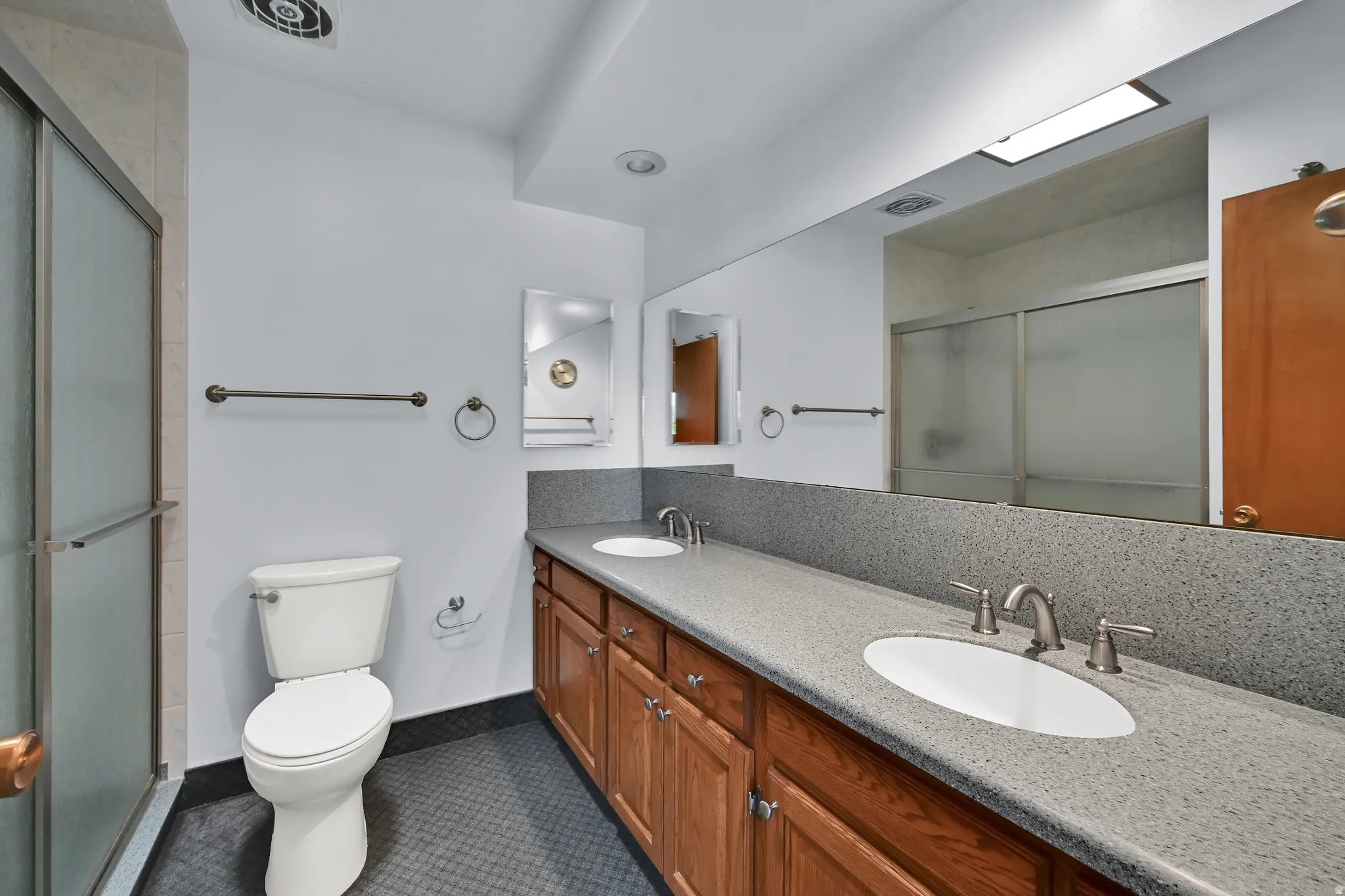 Double vanity with integrated sinks, wood-finish cabinetry, and a textured countertop