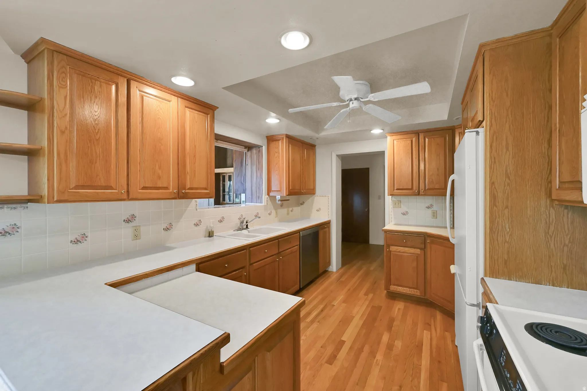 U-shaped kitchen featuring wood-finish cabinetry, white countertops, tile backsplash, and wood-finish flooring
