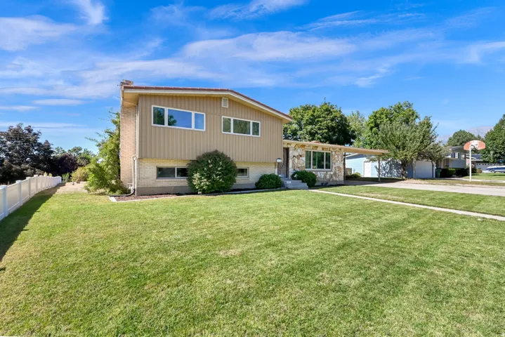Two-story residence featuring a stone and siding exterior, a front lawn with a concrete walkway, and a white fence along the property line
