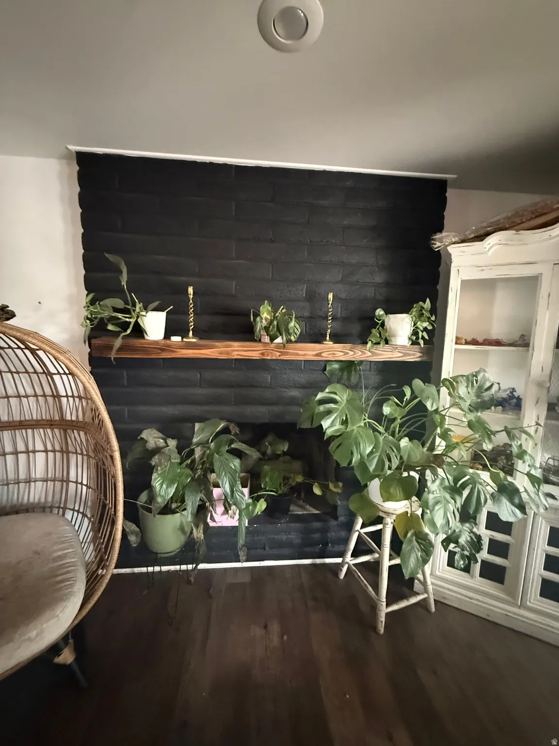 Black-painted brick fireplace with a wood-finish mantel and dark wood-finish flooring