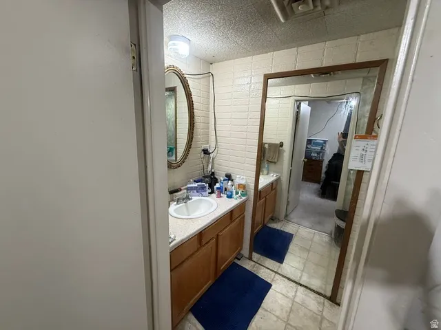 Bathroom featuring a single vanity with wood-finish cabinetry, a white sink, and light-toned countertop