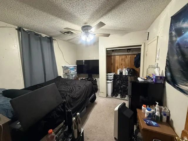 Room featuring a ceiling fan with light fixture and a built-in closet with wood paneling