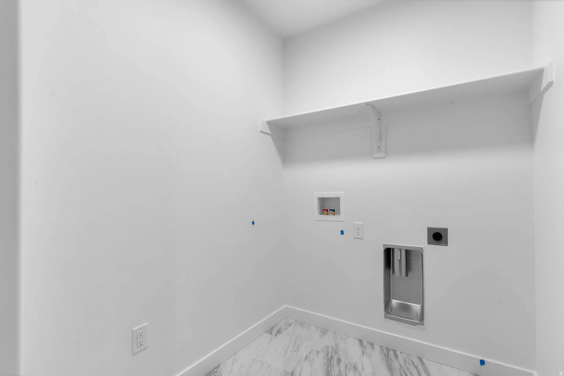 Laundry area featuring a built-in shelf, white walls, and a utility sink