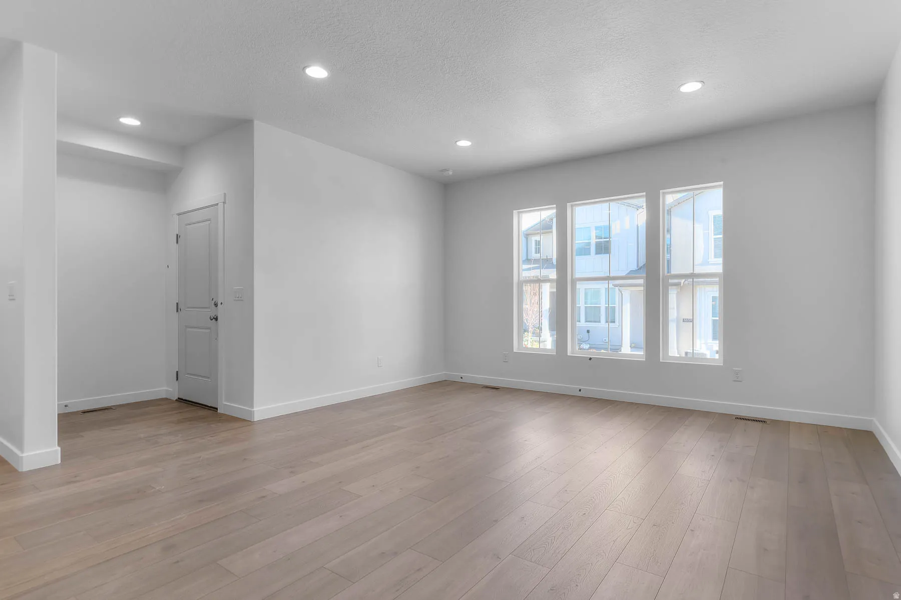 Wood-finish flooring, recessed lighting, and multiple large windows