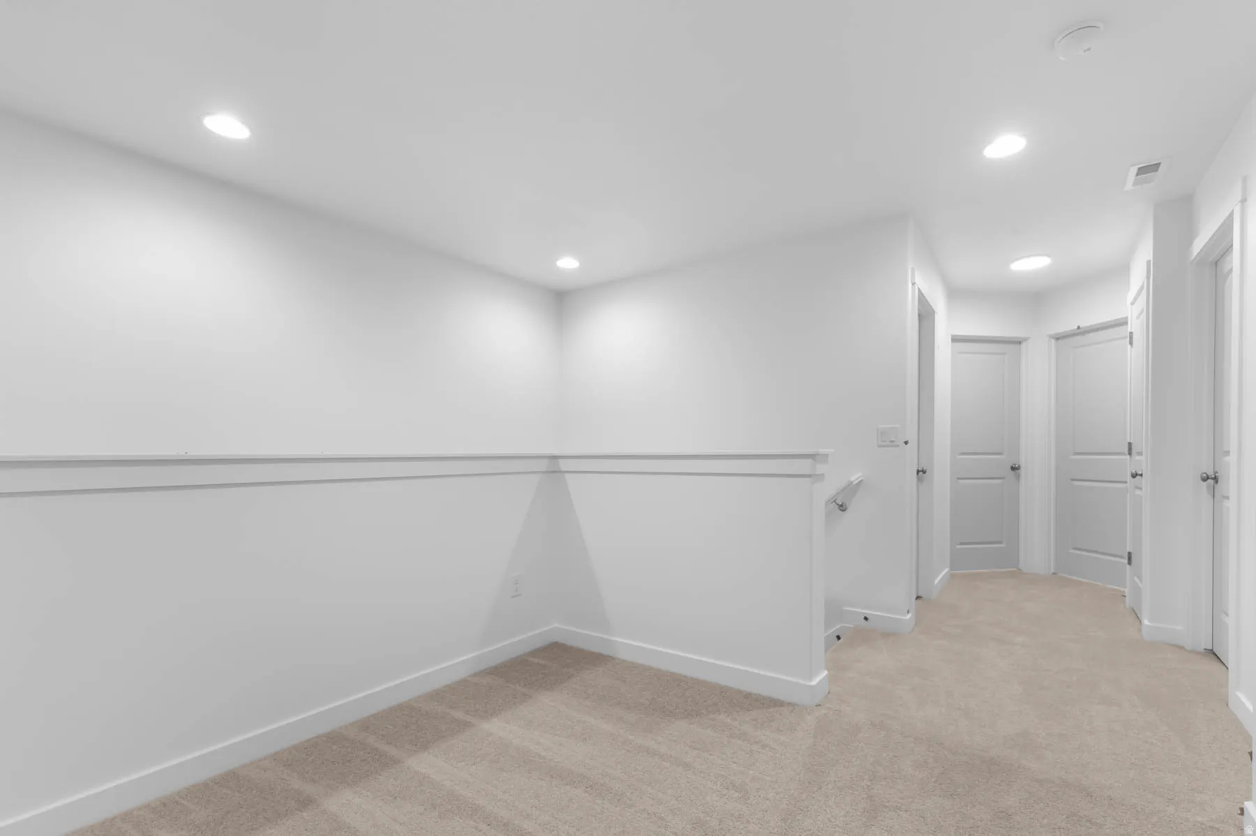 Carpeted landing with recessed lighting, white walls, and white trim