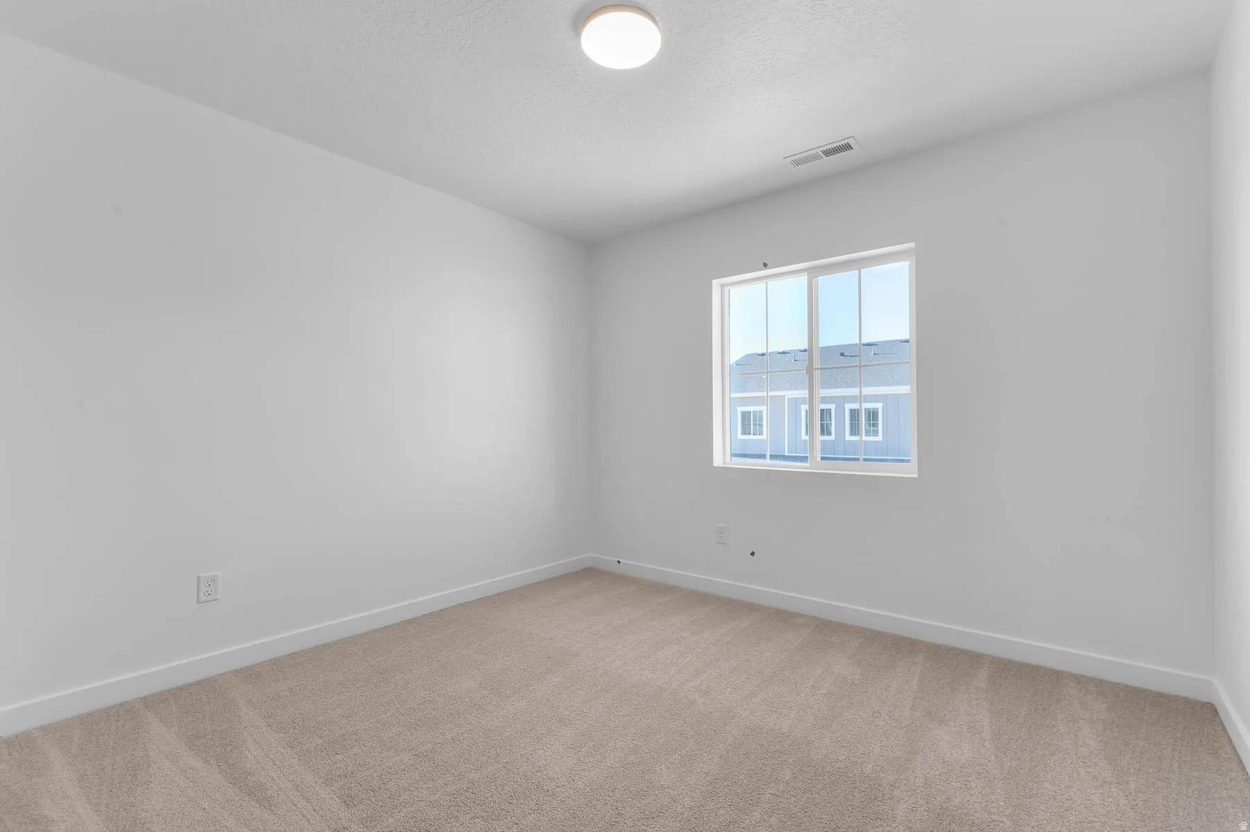 Neutral carpeting, white painted walls, and a multi-pane window