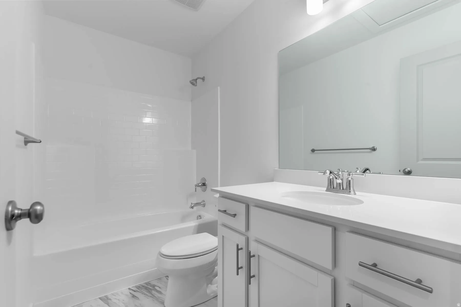 Full bathroom featuring a white vanity with integrated sink, chrome fixtures, and a shower-over-tub combination with subway tile surround