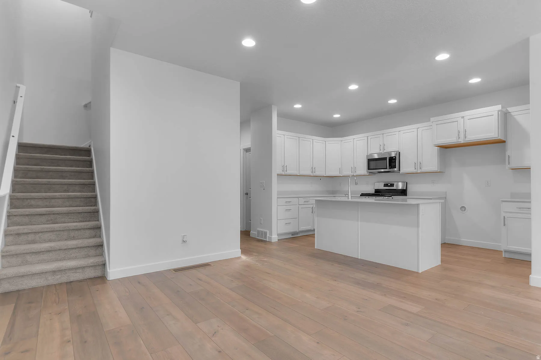 Contemporary kitchen featuring white cabinetry, stainless steel appliances, a center island, and recessed lighting