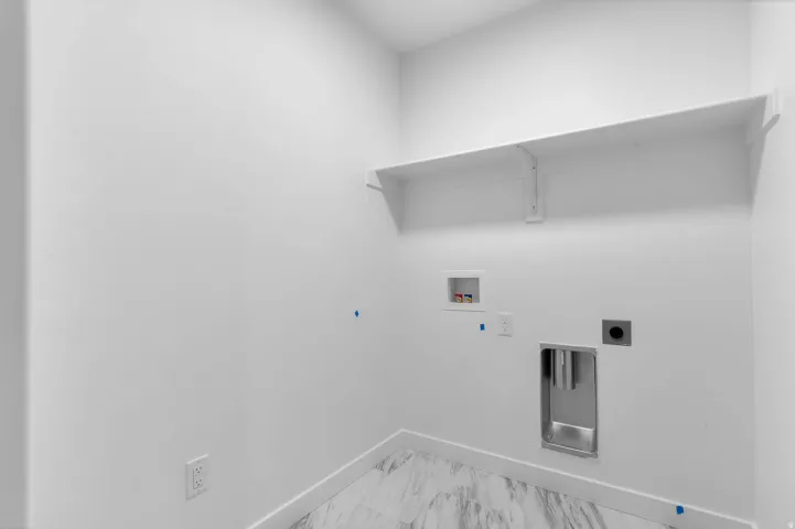 Laundry area featuring a built-in shelf, white walls, and a utility sink