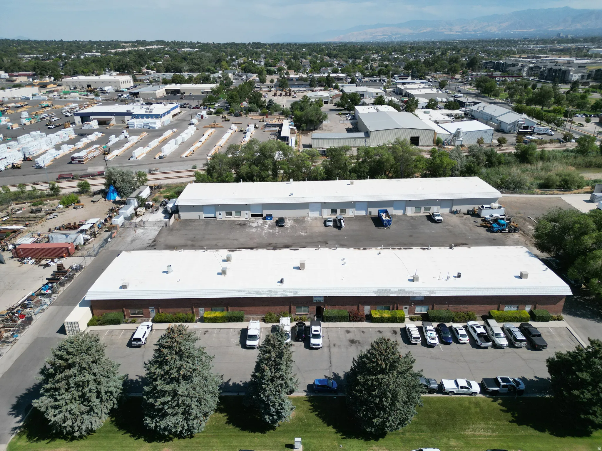 Two commercial buildings with brick and metal exteriors, extensive paved parking, and multiple bay doors