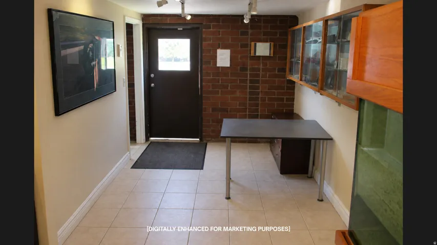 Tiled flooring, exposed brick wall, track lighting, built-in display cabinetry, and a door with an integrated window