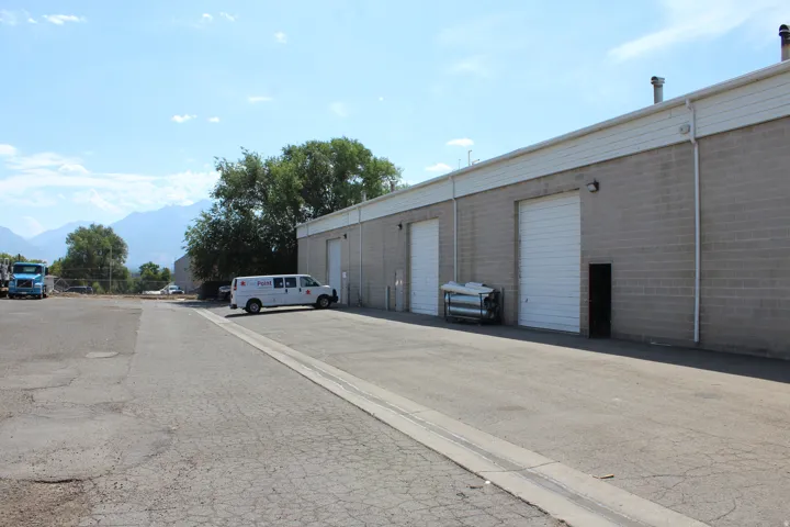 Block construction exterior with multiple drive-in doors, paved parking area, and mountain backdrop