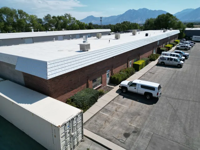 Brick exterior with multiple entry points, a large paved parking area, and a flat roof system