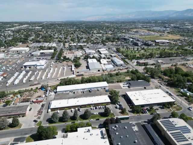 Expansive commercial property featuring multiple buildings, paved parking areas, and mature trees