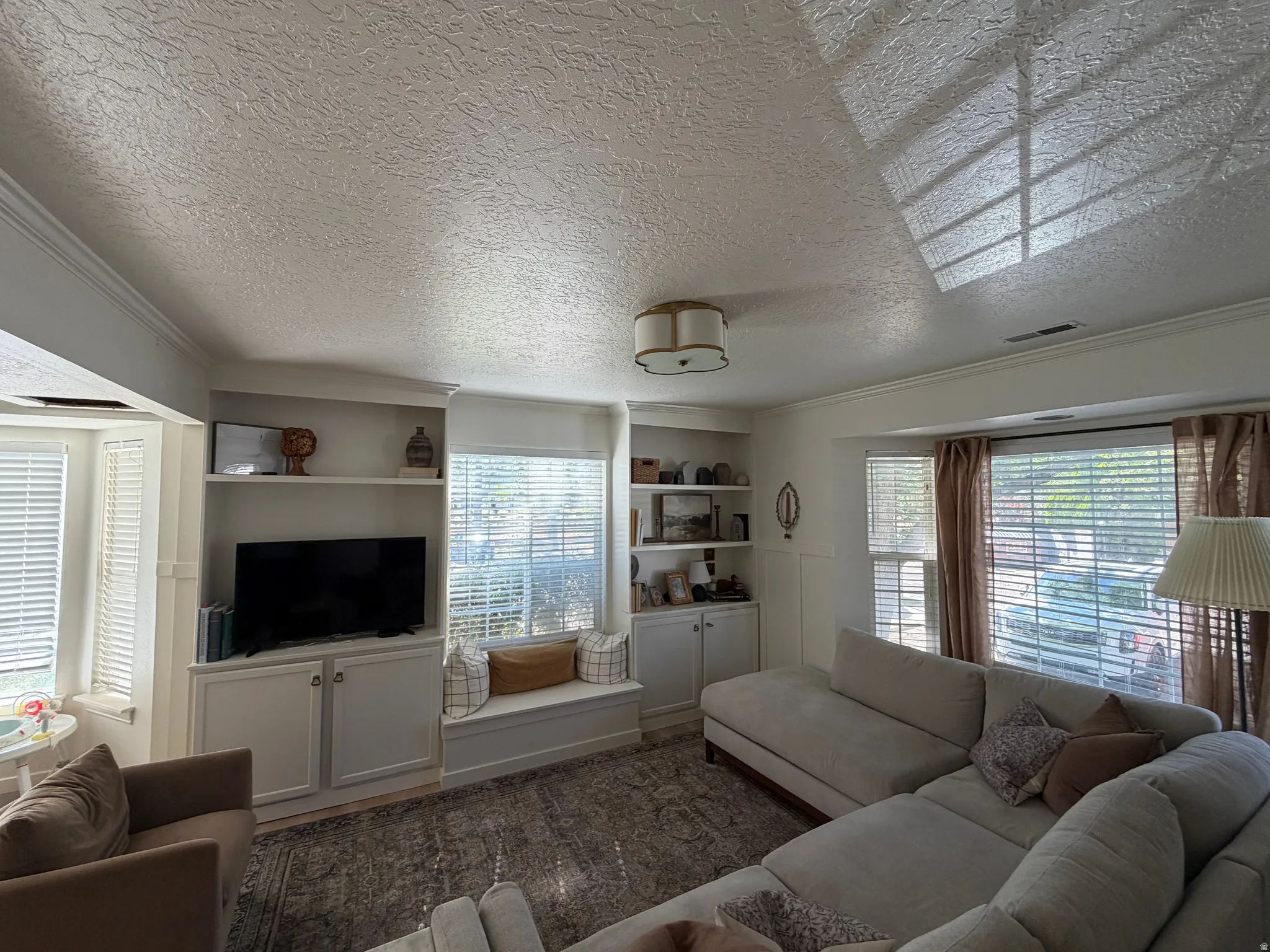 Built-in cabinetry with shelving, integrated window seating, and multiple windows with blinds