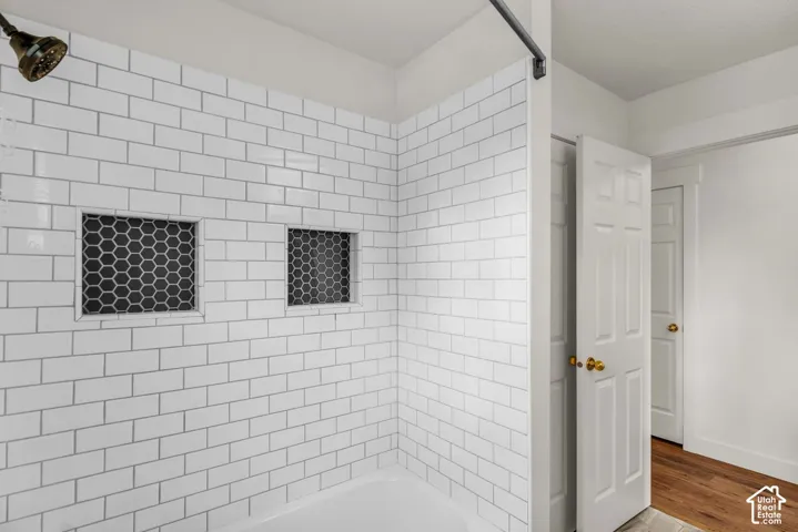 Tub surround featuring white subway tile, integrated hexagonal tile accents, and a bronze-finish shower head