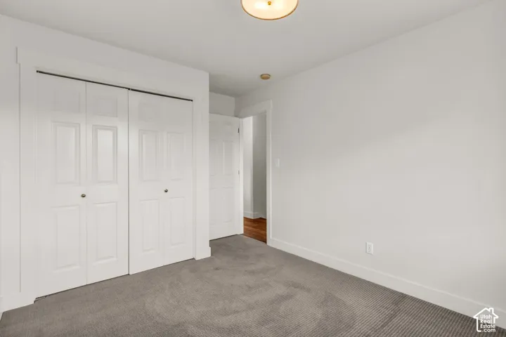 Room featuring neutral wall-to-wall carpeting, white paneled closet doors with trim casing, and a dome ceiling light fixture