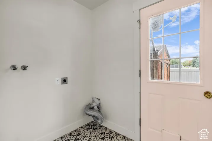 Utility area featuring patterned ceramic tile flooring, dedicated plumbing hookups, and a glass-paned exterior door