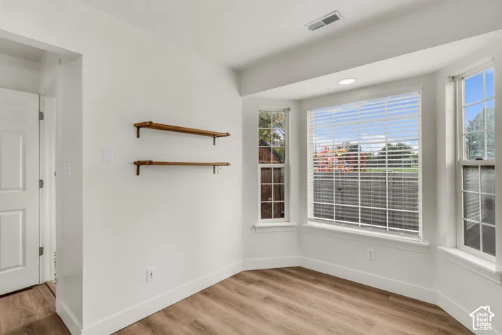 Bay window with natural lighting, wood-finish flooring, and built-in wall shelving