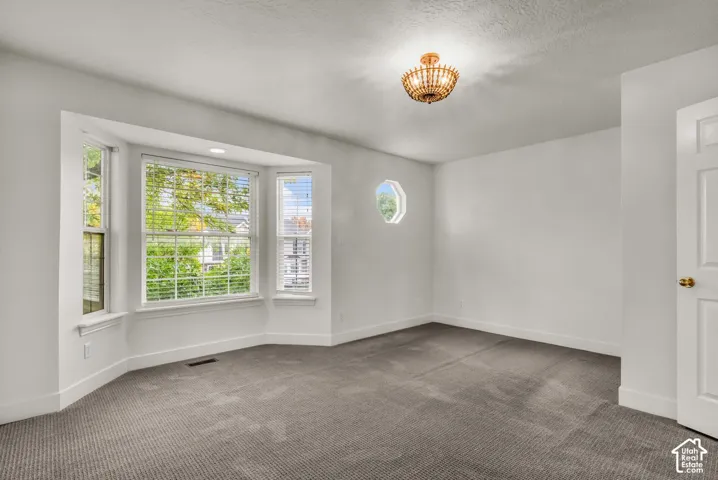 Interior room featuring neutral carpeting, a multi-pane bay window, a decorative octagonal accent window, and a semi-flush mount beaded light fixture