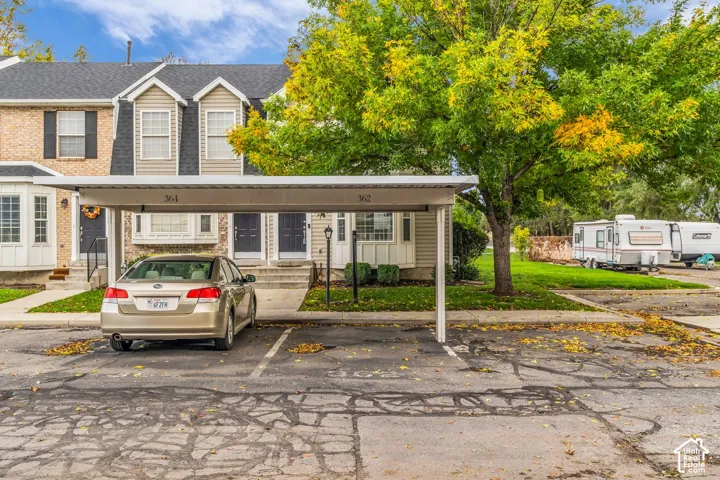 Multi-level townhouse exterior featuring brick and siding facade, covered carport, gabled rooflines, and multi-pane windows