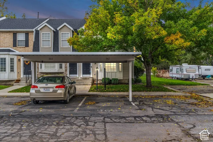 Multi-level exterior with brick and horizontal siding, featuring covered carport parking, bay windows, and steep roof lines
