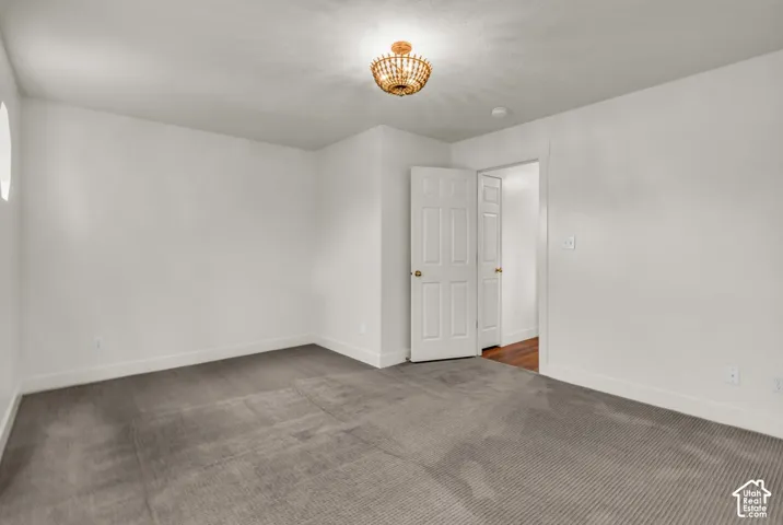 Room featuring neutral-toned carpeting, crisp white walls, a multi-panel interior door, and a decorative semi-flush mount light fixture