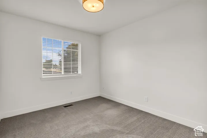 Neutral-toned carpeted flooring, window with white blinds, and a semi-flush mount drum light fixture