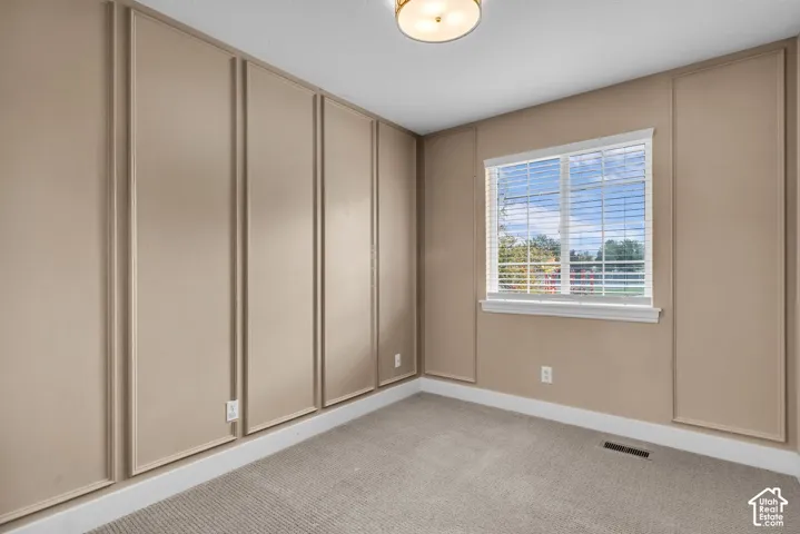 Interior space featuring floor-to-ceiling wall molding, neutral wall tones, carpeted flooring, and a window with horizontal blinds