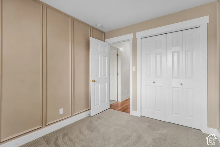 Wall paneling featuring rectangular millwork, neutral carpeting, and a bi-fold closet door with painted trim