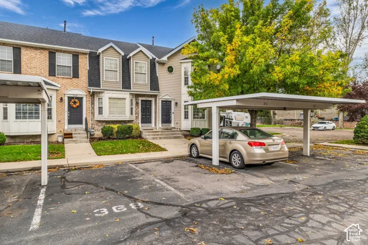 Multi-unit exterior featuring a mix of brick and siding facades, gabled rooflines, bay windows, and dedicated covered parking structures