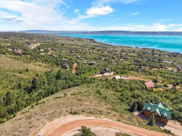 Expansive aerial perspective showcasing multiple residential properties, a large body of water, and surrounding terrain