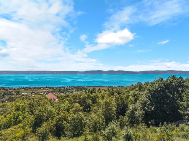 Expansive water body with a distant shore, surrounded by a verdant landscape