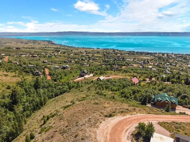 Expansive property featuring a prominent body of water, distant mountain range, and surrounding natural landscape with scattered residences