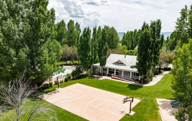 Expansive green space featuring a basketball half-court and a recreational building with an extended porch
