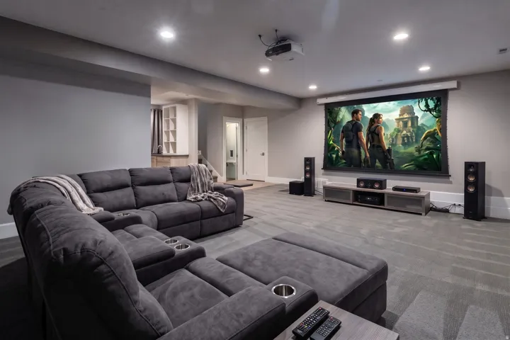 Recessed lighting illuminating the entertainment space, built-in shelving, and light gray wall paint