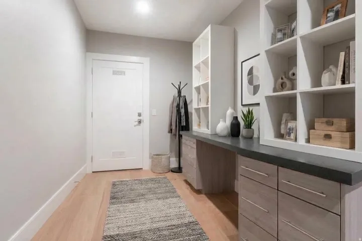 Built-in shelving, integrated desk space, wood-finish flooring, recessed lighting, and a solid core door