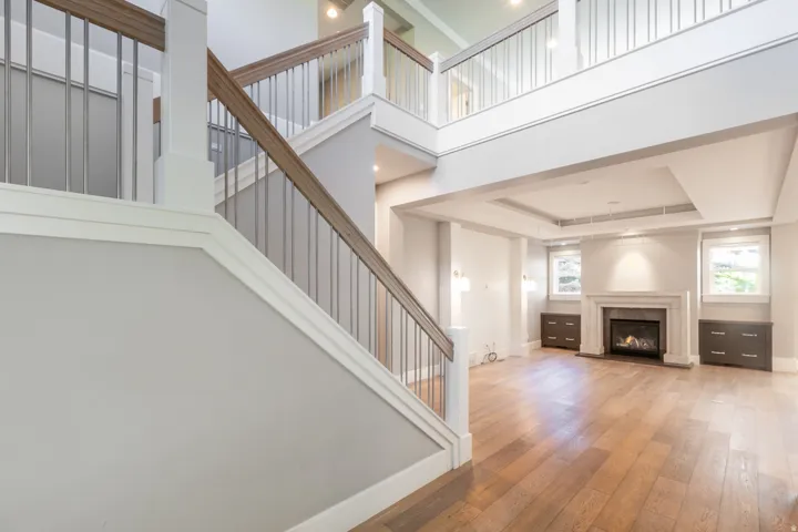 Hardwood flooring, two-story ceiling, coffered ceiling, fireplace with stone surround, and built-in cabinetry