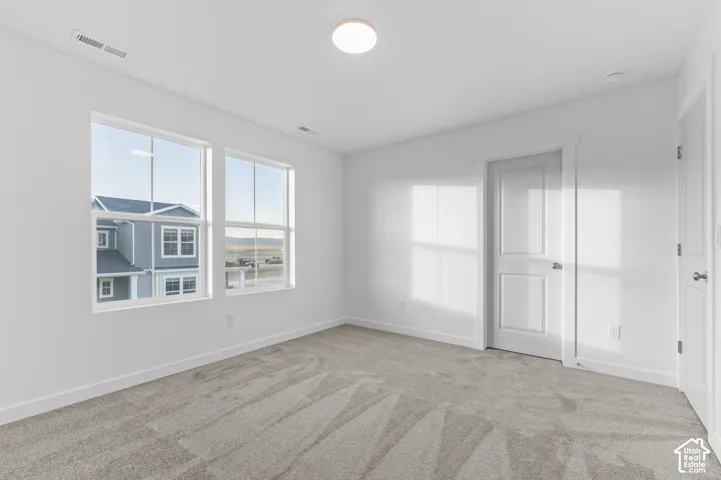 Neutral-toned carpeting, dual-pane windows with grids, two-panel interior doors, and a central flush-mount ceiling light fixture