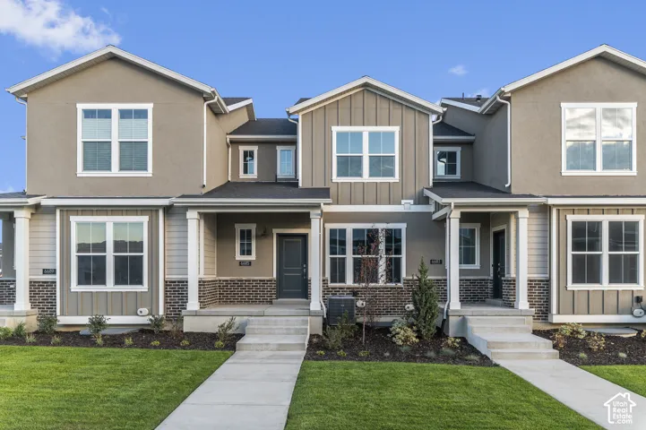 Multi-unit exterior featuring a combination of horizontal siding, vertical board-and-batten siding, and dark brick masonry, complemented by covered front porches with structural columns and concrete walkways