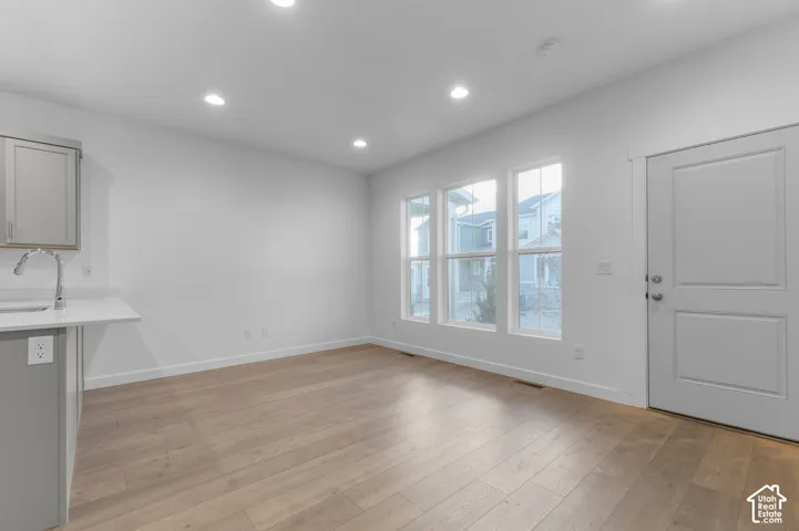 Wood-finish flooring, recessed lighting, neutral wall palette, multi-pane windows, and shaker-style cabinetry with a countertop extension