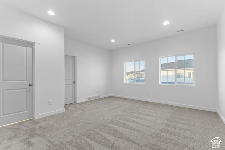 Neutral-toned carpeting, recessed ceiling lighting, two panel-style interior doors, and dual-pane windows