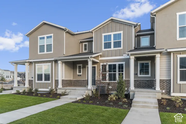 Multi-unit exterior featuring board-and-batten siding, brick masonry detailing, covered front porches with square columns, and concrete walkways