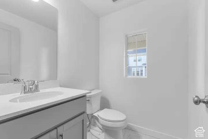 Gray vanity featuring a stone-composite countertop, undermount sink with a polished chrome faucet, large rectangular wall-mounted mirror, and tile flooring