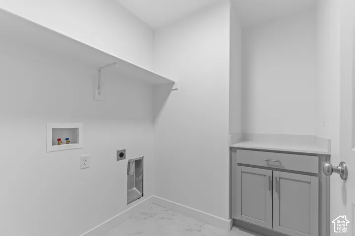 Laundry room featuring white cabinetry, quartz countertop, built-in shelving, and stone-finish flooring