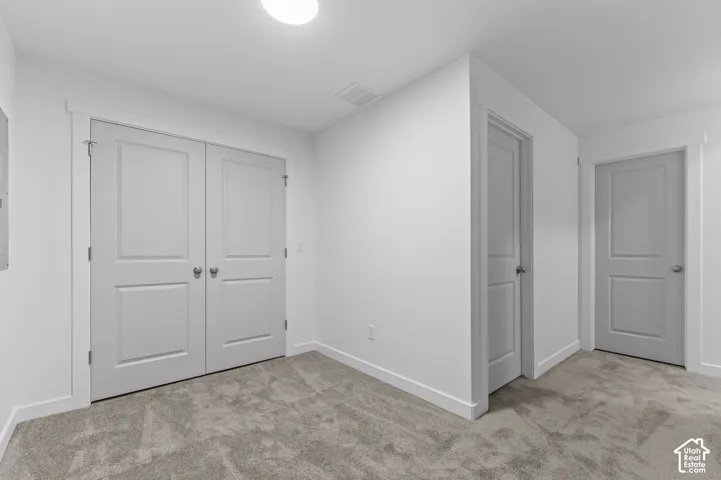 Neutral-toned carpeted flooring, two-panel interior doors, and solid-core double closet doors