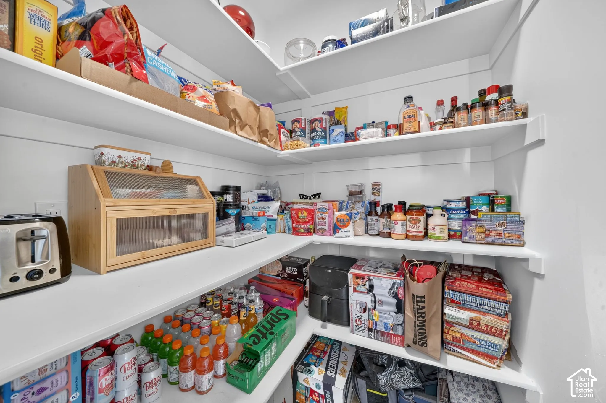 Spacious pantry featuring multiple curved shelving units with ample storage capacity, built-in wooden bread box with glass front, and organized display of canned goods and dry goods throughout