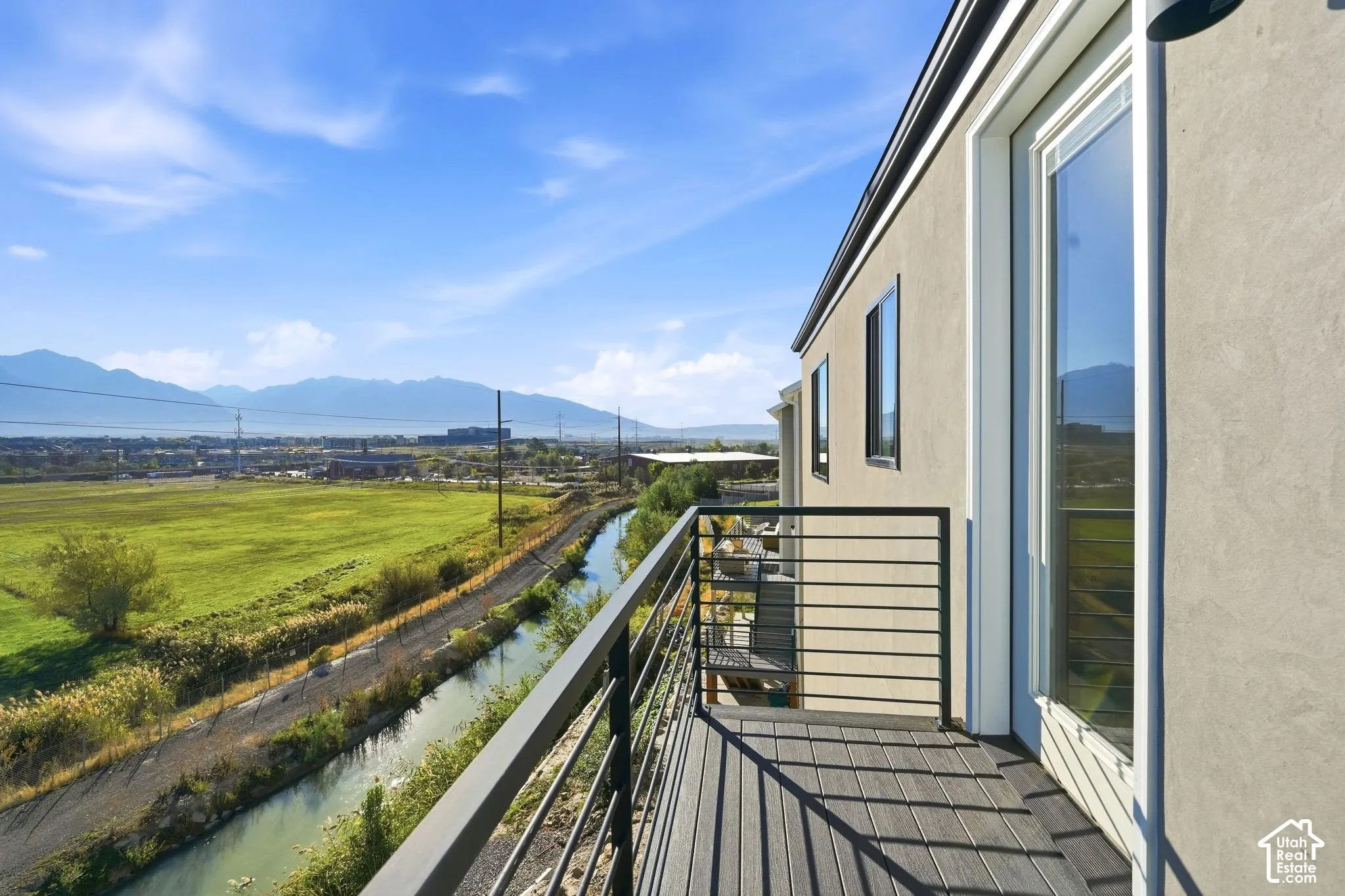 Balcony with composite decking, black metal railing, and stucco exterior