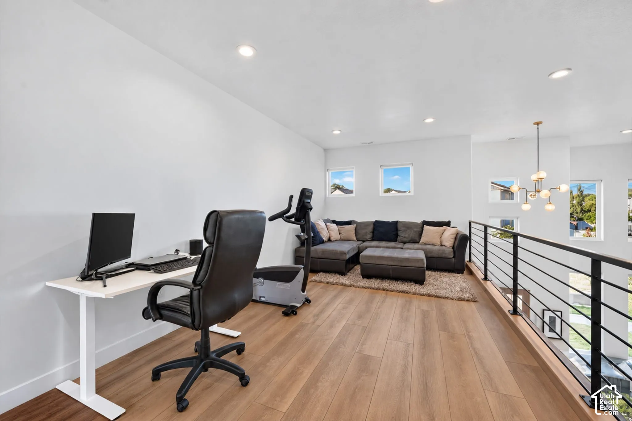 Loft area with wood-finish flooring, recessed lighting, and a contemporary chandelier
