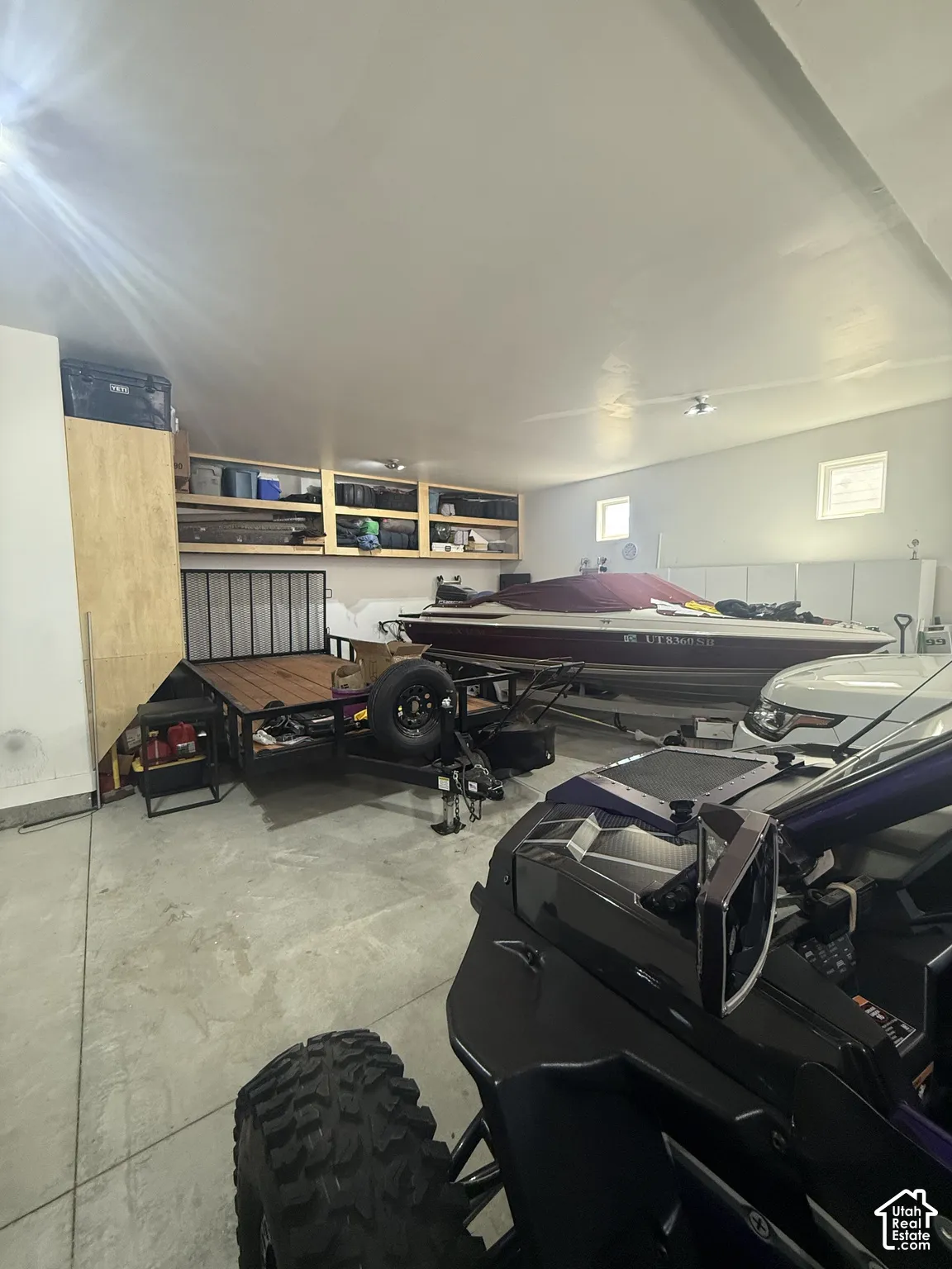 Spacious garage featuring concrete flooring and built-in wall shelving